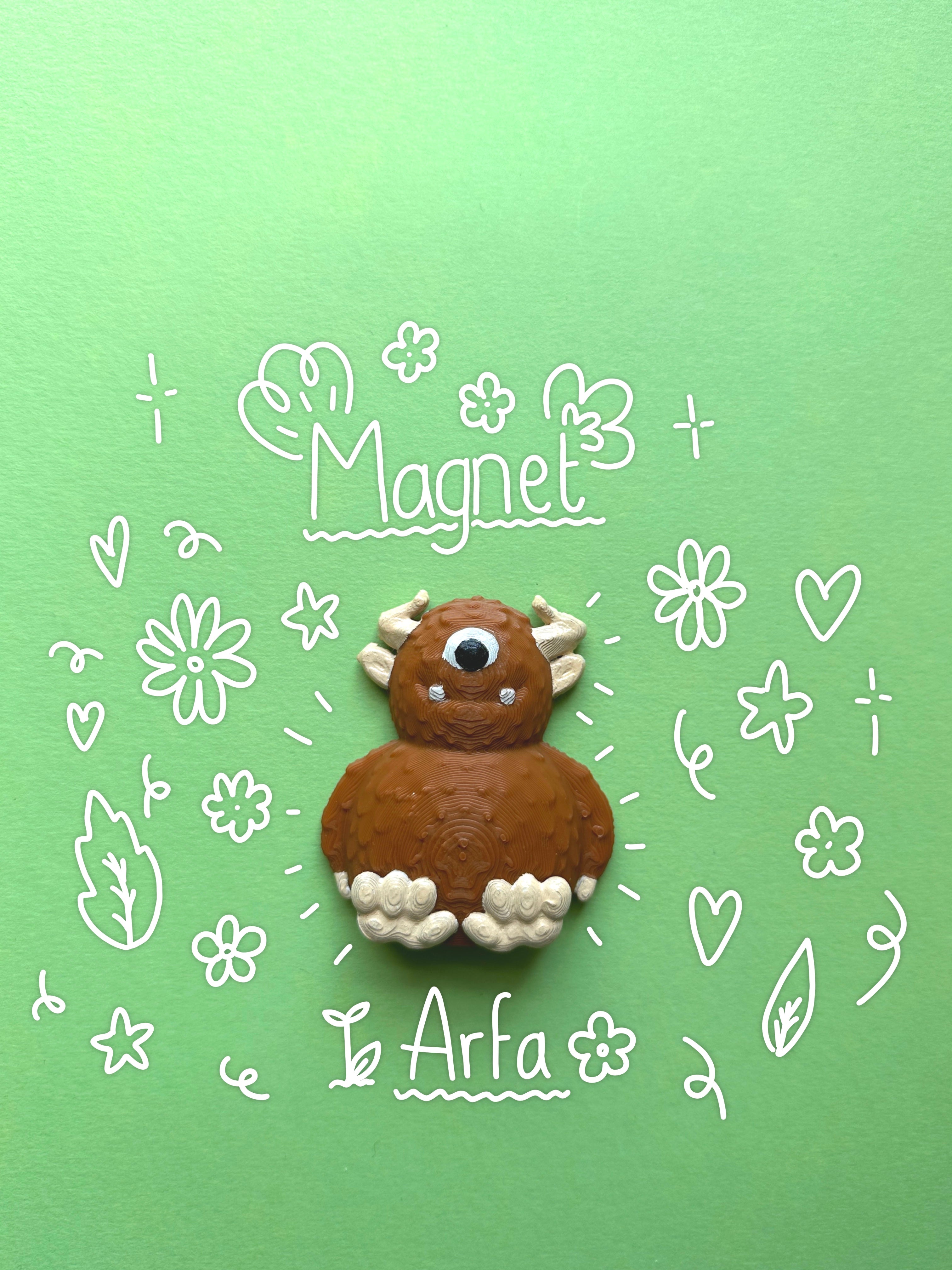 A handmade brown and white  3D magnet shaped like a cute monster, displayed on a light green background with white hand-drawn doodles and the words 'Magnet' and 'Arfa' with flower and leaf doodles surrounding it.