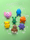 Six colourful monster-shaped magnets arranged on a light green background with hand-drawn white labels and doodles naming them: Tipley, Hairy, Grumble, Syd, Twain, Arfa, and Oggy.