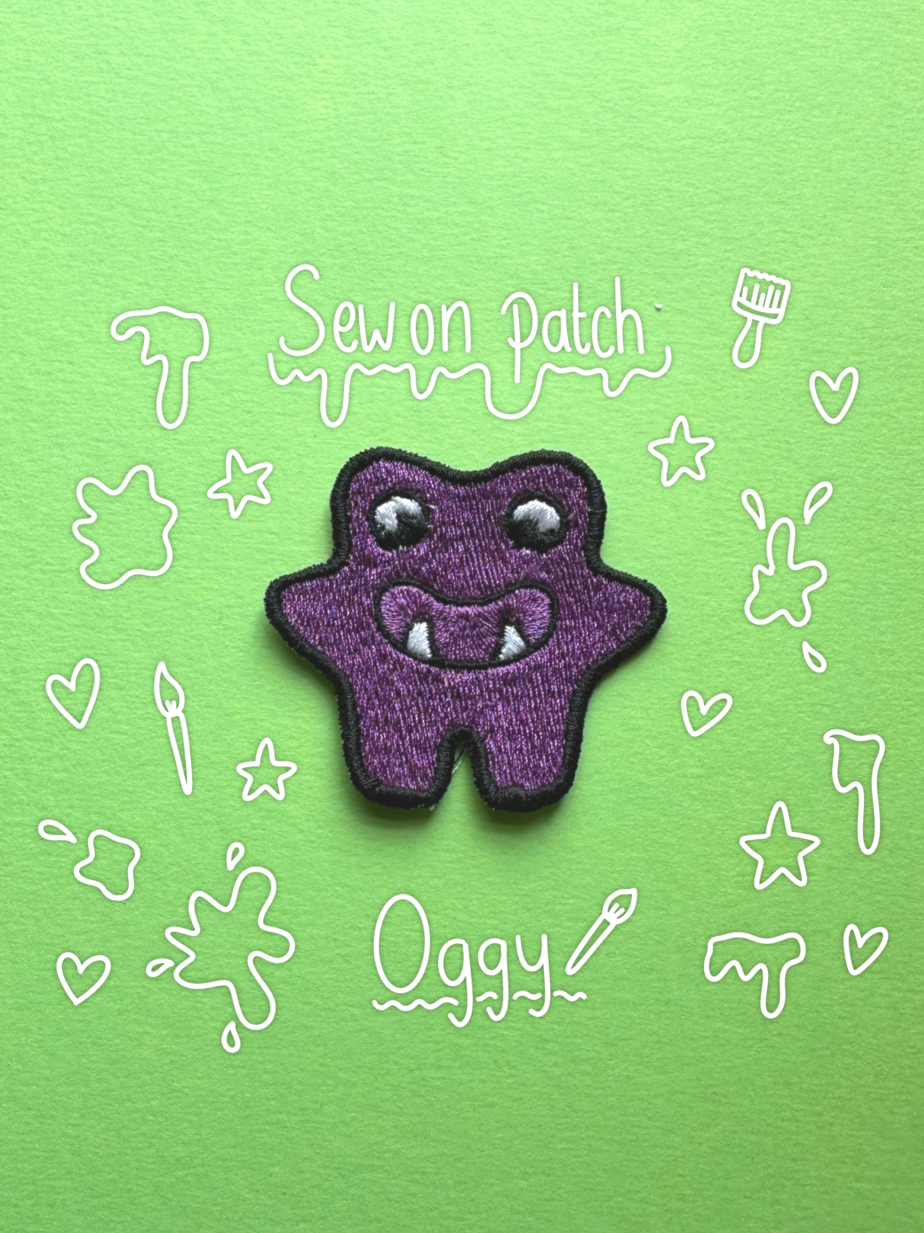 A purple monster-shaped embroidered patch with white eyes and fangs, placed on a bright green background with white doodle-style text reading 'Sew on Patch' and 'Oggy'.